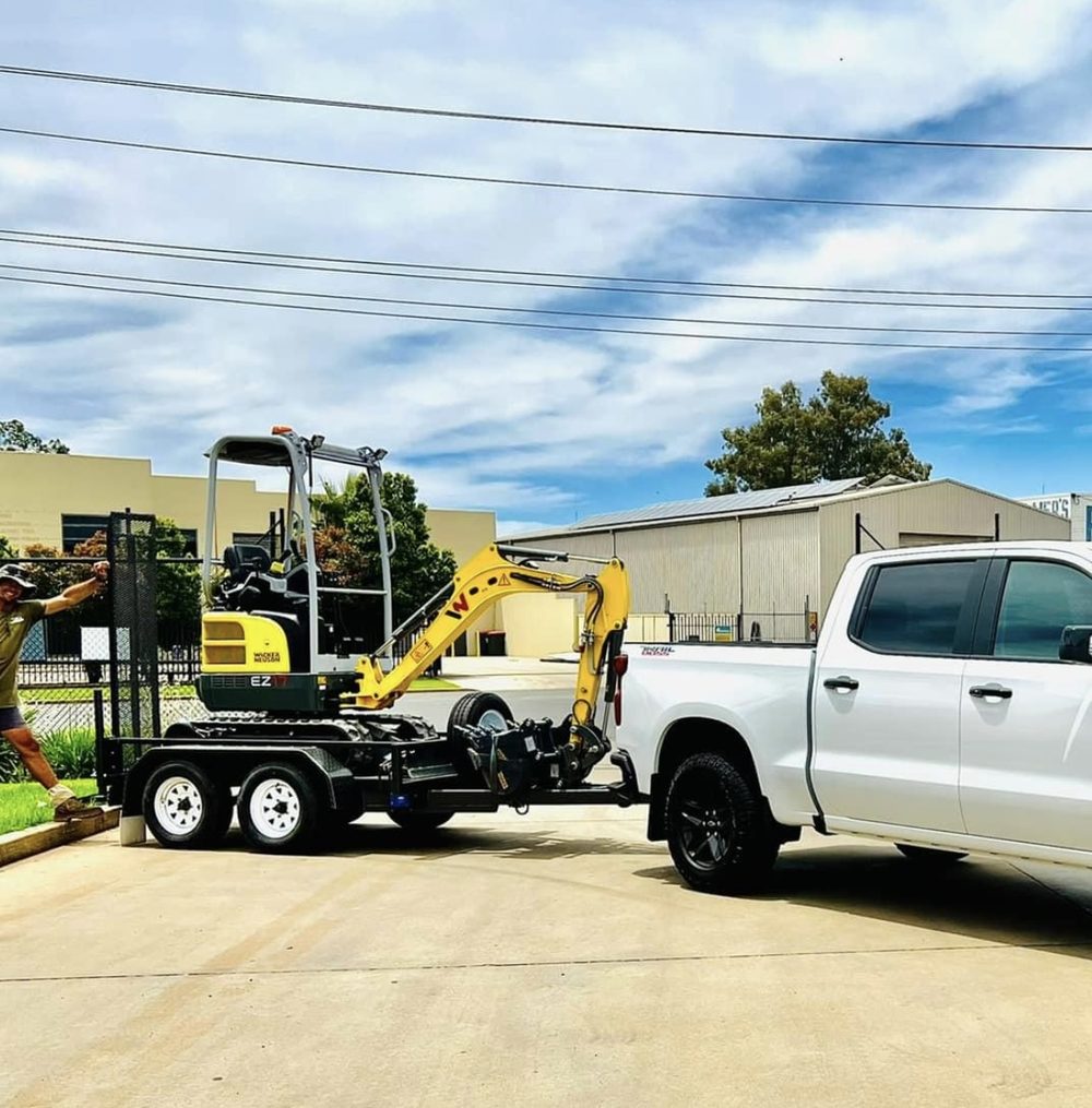 Riverina Diggers excavator loaded on a trailer behind a ute, ready for delivery in Griffith