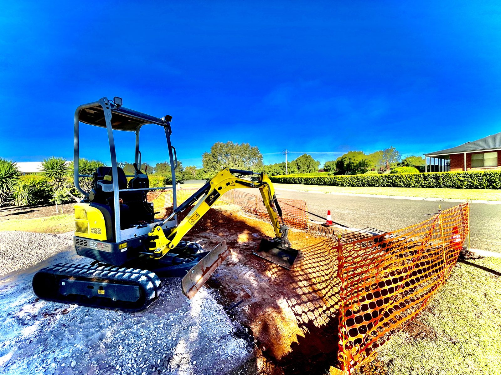 Riverina Diggers 1.7t excavator digging a driveway crossover behind safety fencing on a Griffith street