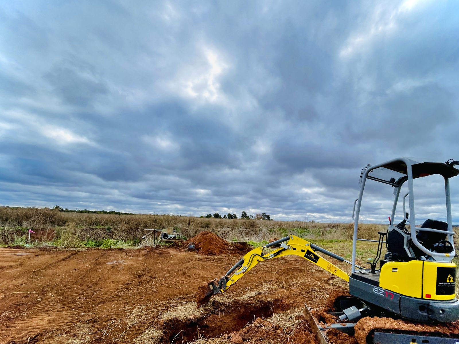 Riverina Diggers mini excavator beside a levelled pad with spoil heaped alongside